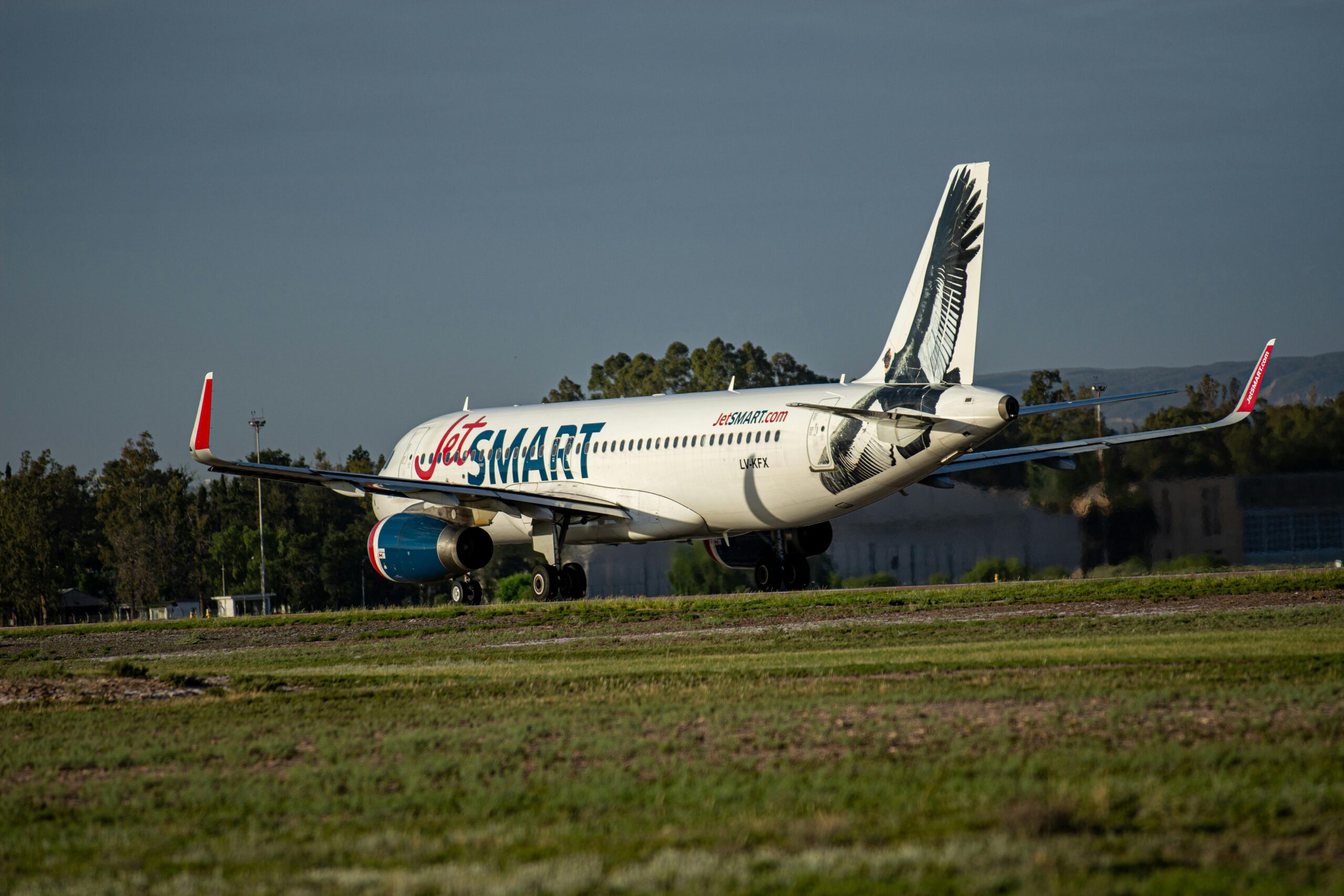 JetSMART-Flugzeug rollt mit markantem Heckdesign auf der Landebahn. Klarer Himmel und Tageseinstellung.
