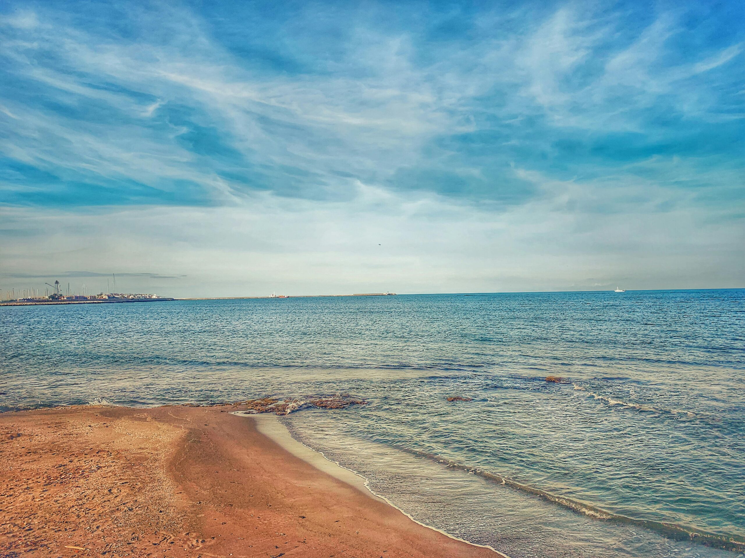 Malerische Aussicht auf einen ruhigen spanischen Strand mit azurblauem Wasser unter einem klaren blauen Himmel, perfekt zum Reisen und Entspannen.